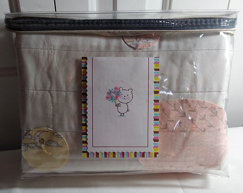 Folded quilt in vinyl zippered bag with card that includes quilt care instructions