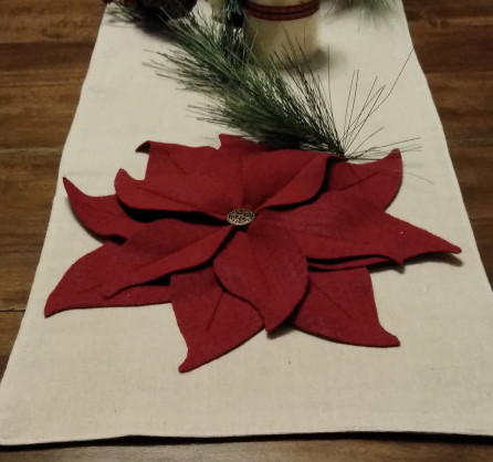 Felt poinsettia on table tunner with candle and greenery