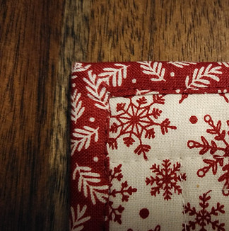 Machine stitched binding and mitered corner of Christmas mug rug