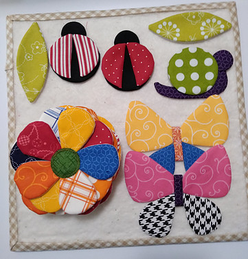 Fabric applique leaves, butterfy, snail, lady bug and flowers using Kimberbell Basic fabric line by Maywood Studio.  These will be sewn onto Secret Garden quilt.
