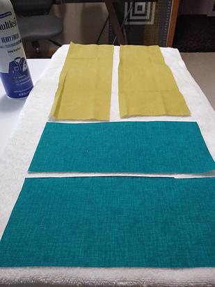 Blue and green fabric rectangles on a white towel eady to be starched