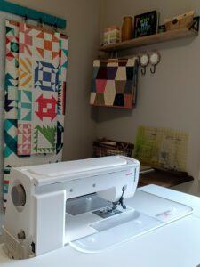 Sewing room with Janome 9450 sewing machine and quilts in background