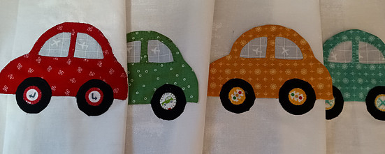 Four fabric cars in red, green, orange and blue, appliqued onto a fabric panel