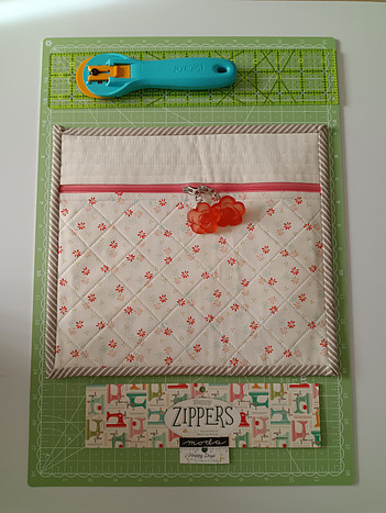 Rotary cutter with cutting mat, finished project bag with labels from maerials used: Lori Holt Happy Zipper and Sheri & Chelsea Happy Days fabrics