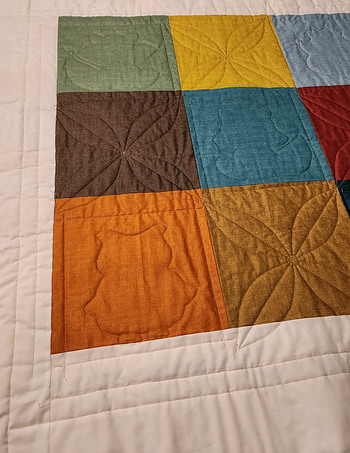 Quilt back made from 9 square blocks of fabric with quilt stitching