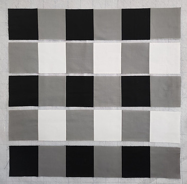 Five rows of black, white and gray squares of fabric
