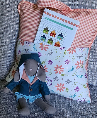 Fabric reading pillow and bunny wearing a hooded jacket.