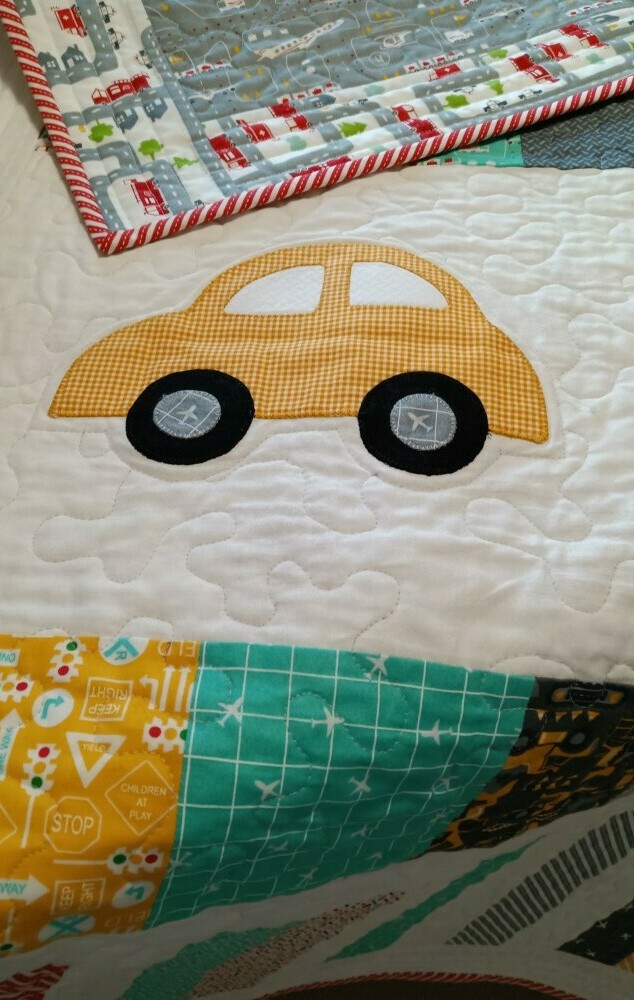 Free motion quilted white background with yello fabric car applique on baby quilt