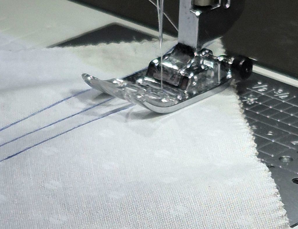 Fabric on sewing machine sewn on the diagonal to create two HST.