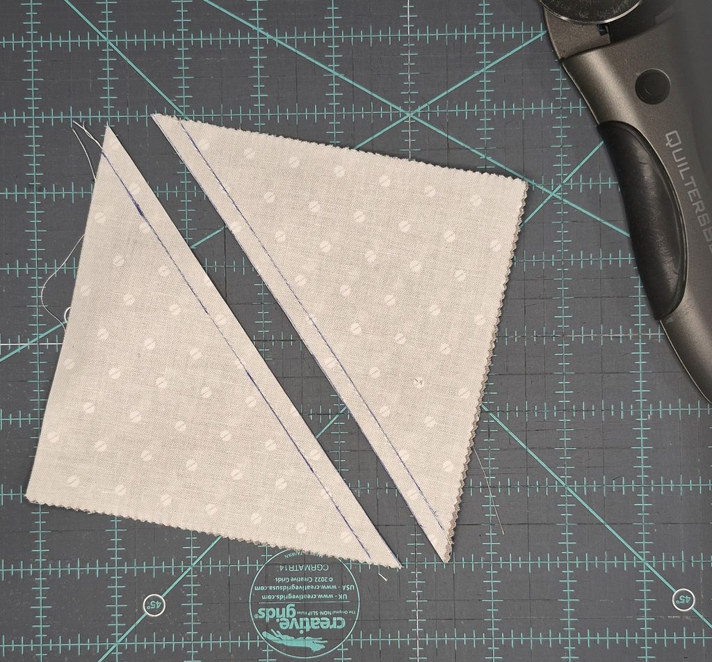 Fabric square with diagonal stitching and cut along the center cut line to form two triangles.